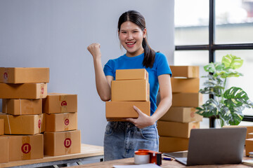 Small business entrepreneur SME freelance asian woman holding boxs working at home office, online marketing packaging delivery box, SME e-commerce concept
