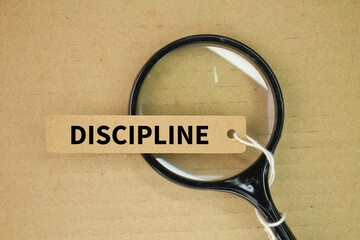 magnifying glass and tag paper with the word discipline. practice of training oneself to follow rules or a code of behavior, often through self-control and perseverance