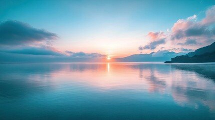 Naklejka premium A serene ocean view at sunrise, with soft blue hues in the sky reflecting on the calm waters below, creating a peaceful and calming scene.