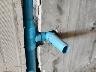 A bright blue pipes attached to a solid concrete wall