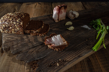 Snack with dark bread and lard. Sandwich with dark bread and bacon. Snack country style Low key.