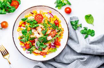 Salad with shrimps, corn, avocado, tomatoes, lettuce and onion on white background. Top view