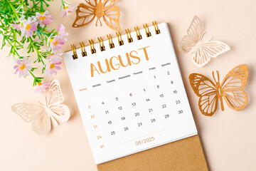 August 2025 desk calendar and paper butterfly with flower.