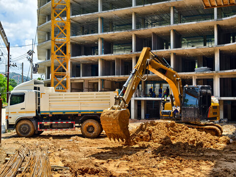 Excavator loads ground into a dump truck at a construction site - Powered by Adobe