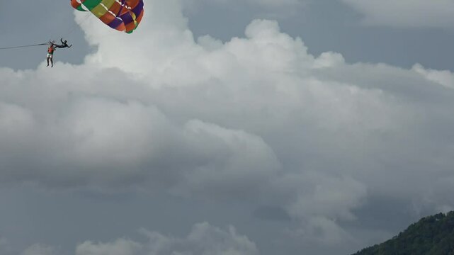 Blue sky view with  unidentified tourist on parasailing flying by. Tourism concept