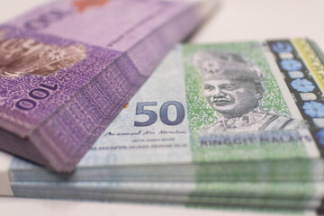 Fototapeta premium Purple and green Malaysian Ringgit banknotes stacked together, representing Malaysia's currency, finance, and economic transactions in the region.