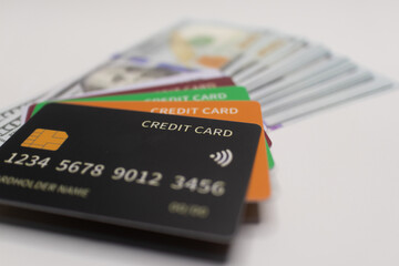 Black credit card placed on a stack of blue and gold US  dollar banknotes, representing premium finance, cashless payments, and luxury banking .