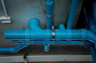 A bright blue pipes attached to a solid concrete wall