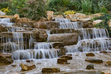 Obraz premium A Beautiful Tranquil Waterfall Cascade Flows Over Natural Stone Steps into a Peaceful Oasis
