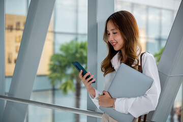 Professional woman in white shirt multitasking with laptop and phone in airport. Productive work...