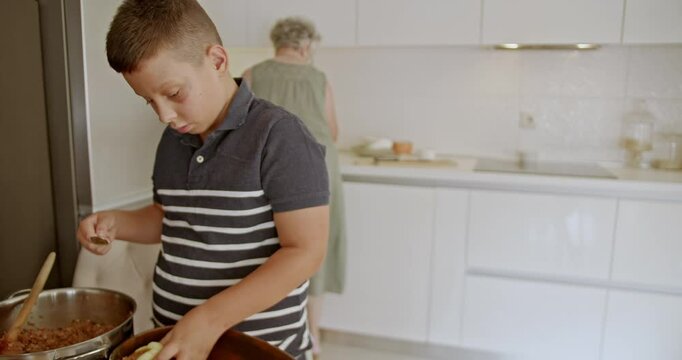 Grandmother and her grandson share quality time in the kitchen as they prepare a meal of stuffed bell peppers together.