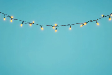 Bright Christmas fairy lights on a flat blue background with space for text