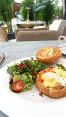 Eggs Benedict on buttery croissant topped with fresh greens and pomegranate seeds offers healthy indulgence This farm-to-table dish balances rich flavors with eco-friendly, nutrient-packed ingredient 