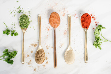 Five different spices in spoons on a table