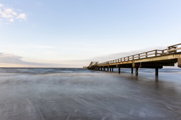 Obraz premium Long exposure waves and pier stretching out to sea