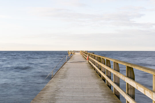 Wooden pier stretching out towards empty horizon