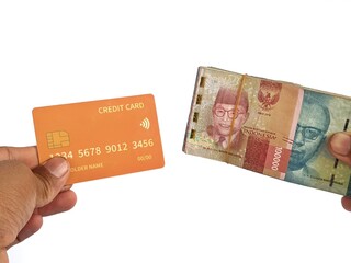 Hand holding a credit card and Rupiah denominations on a white background