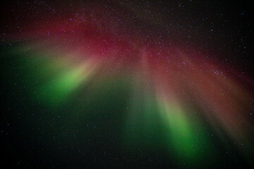 Explosive red and green Northern Lights / Aurora Borealis high in the sky