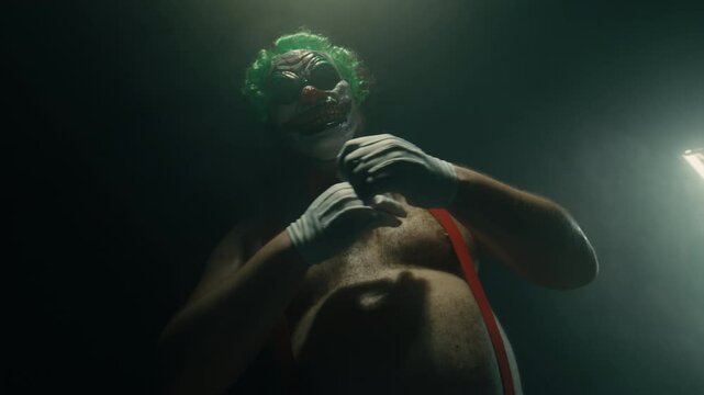 Scary clown posing with arms crossed on dark background