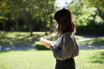 Fototapeta premium 夏の公園で静かに読書している女子高校生の姿