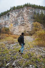 Embarking on an adventure, a hiker stands in awe against a breathtaking majestic cliff landscape adorned with vibrant autumn colors