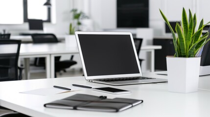 Front view laptop on white table. There is paper and a pen holder nearby. In modern office space