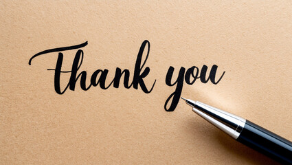 Elegant black script 'Thank you' with pen on textured paper background showcasing gratitude.