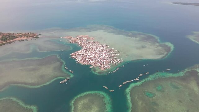 Aerial view of crowded fishing village with boats and houses by the ocean, Bungin Island, Sumbawa NTB, Indonesia.
