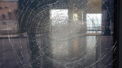 Reflections in a shop window cracked by a violent impact photographed from the street.