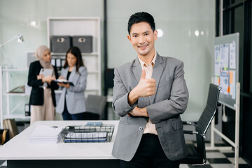 Attractive Asian male office worker business suits smiling at camera in office . teamwork startup concept