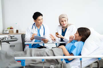 Fototapeta premium Hospital Ward Male and Male Professional Asian Doctors Talk with a Patient, Give Health Care Advice, Recommend Treatment Plan