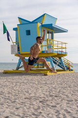 Young male tourist jumping in front of a lifeguard stand in Miami Beach.