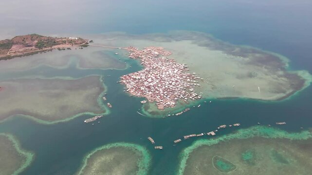 Aerial view of a dense fishing village surrounded by blue sea and coral reefs in Bungin Island, Sumbawa NTB, Indonesia.