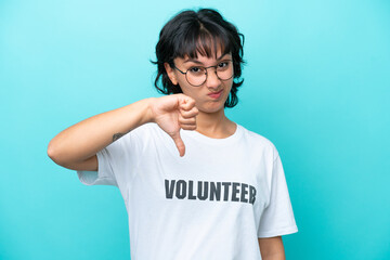 Young volunteer Argentinian woman isolated on blue background showing thumb down with negative...