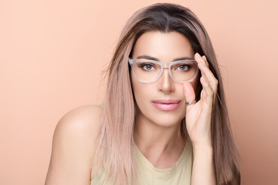 Portrait of a woman with stylish eyeglasses on peach background