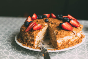 imperfect homemade freshly baked honey cake decorated with berries, cut