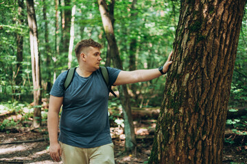 Man with backpack Touch of tree in the forest. Caring for the environment. The ecology the concept of saving the world and love nature by human