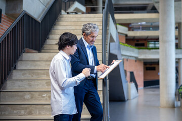 Asian senior professor is giving advice  to the college student on the research thesis while sitting in the university faculty for education, academic and business