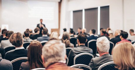 Speaker giving a talk in conference hall at business event. Rear view of unrecognizable people in...