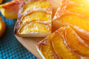 A dessert made of sliced peaches is on a wooden cutting board. The dessert is covered in sugar and looks delicious.