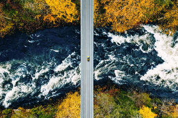 Aerial view of fall forest and blue river with bridge in Finland.