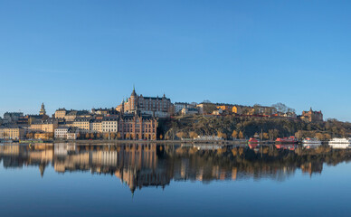 Obraz premium Panorama view the district Södermalm hill Maria Berget, board walk path vista point Montelius vägen on the cliffs at the bay Riddarfjärden, a sunny summer morning in Stockholm