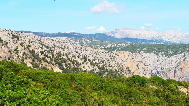 Gorropu canyon hiking trail valley to famous gorge in Sardinia with Sardinian mountains cliff nature forest landscape, panning shot in summer of Italy