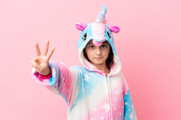 Little caucasian woman wearing a unicorn pajama isolated on pink background happy and counting...