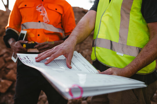 Builders holding a blueprint at the construction site.