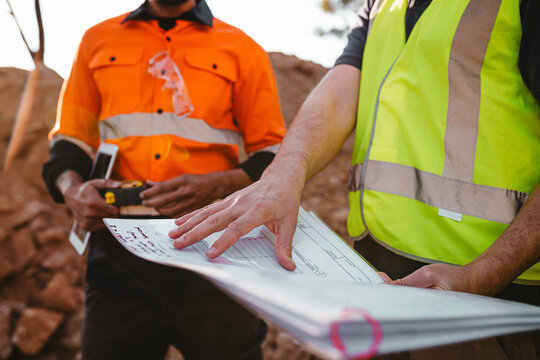 Builders holding a blueprint at the construction site