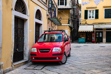 Narrow street of the old town with colorful houses and red car parked on a side in Europe