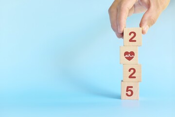 Year 2025 health priority concept. Wooden blocks on blue background with icon.