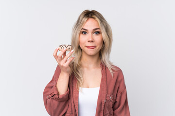 Teenager blonde girl over isolated white background holding a donut