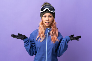 Skier teenager girl with snowboarding glasses over isolated purple background with shocked facial...